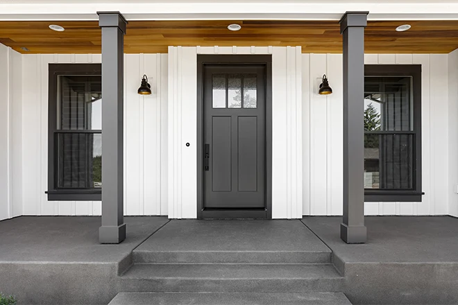 Home exterior with white vertical wood siding and black front door