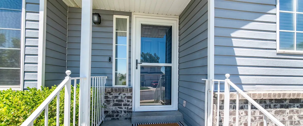 Front porch of a house with glass storm door with sidelight